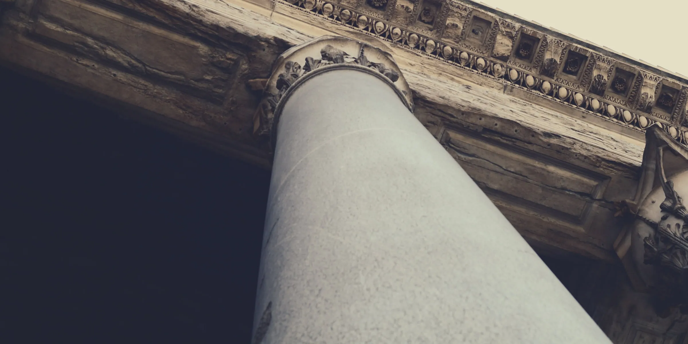 A fluted granite column and the coffered stone entablature above it, seen from below.