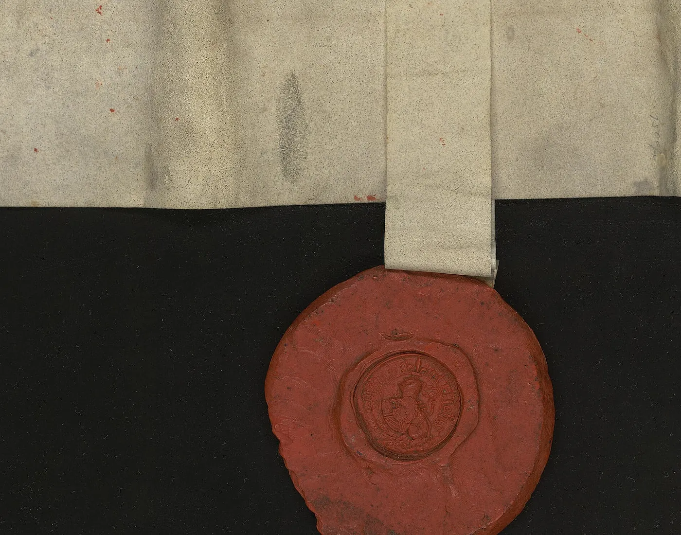 A folded vellum commission of 1405 with its red wax seal still hanging from the tag, photographed against black.